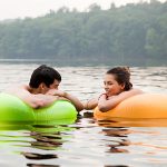 Young couple on inflatable rings on lake