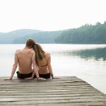 Couple sitting on pier looking over lake
