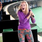Young woman looking back in excitement after g women playing golf at TopGolf