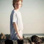 Portrait of a young boy and his dog at sunset on a quiet beach in Mexico.
